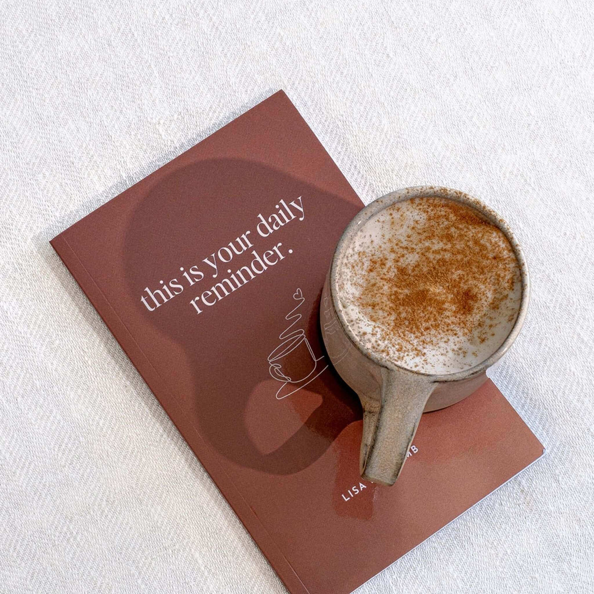 Terracotta cover with a line-drawn coffee cup, a cinnamon-dusted coffee resting on top, seen from above