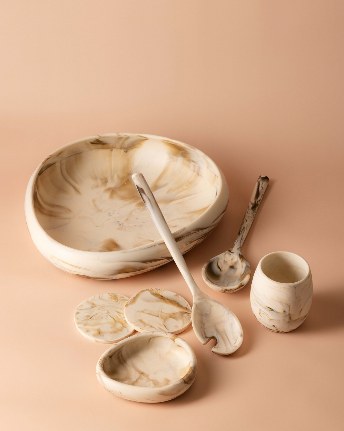 Tiramisu resin range on peach: a tumbler, large bowl, small bowl, salad servers and coasters