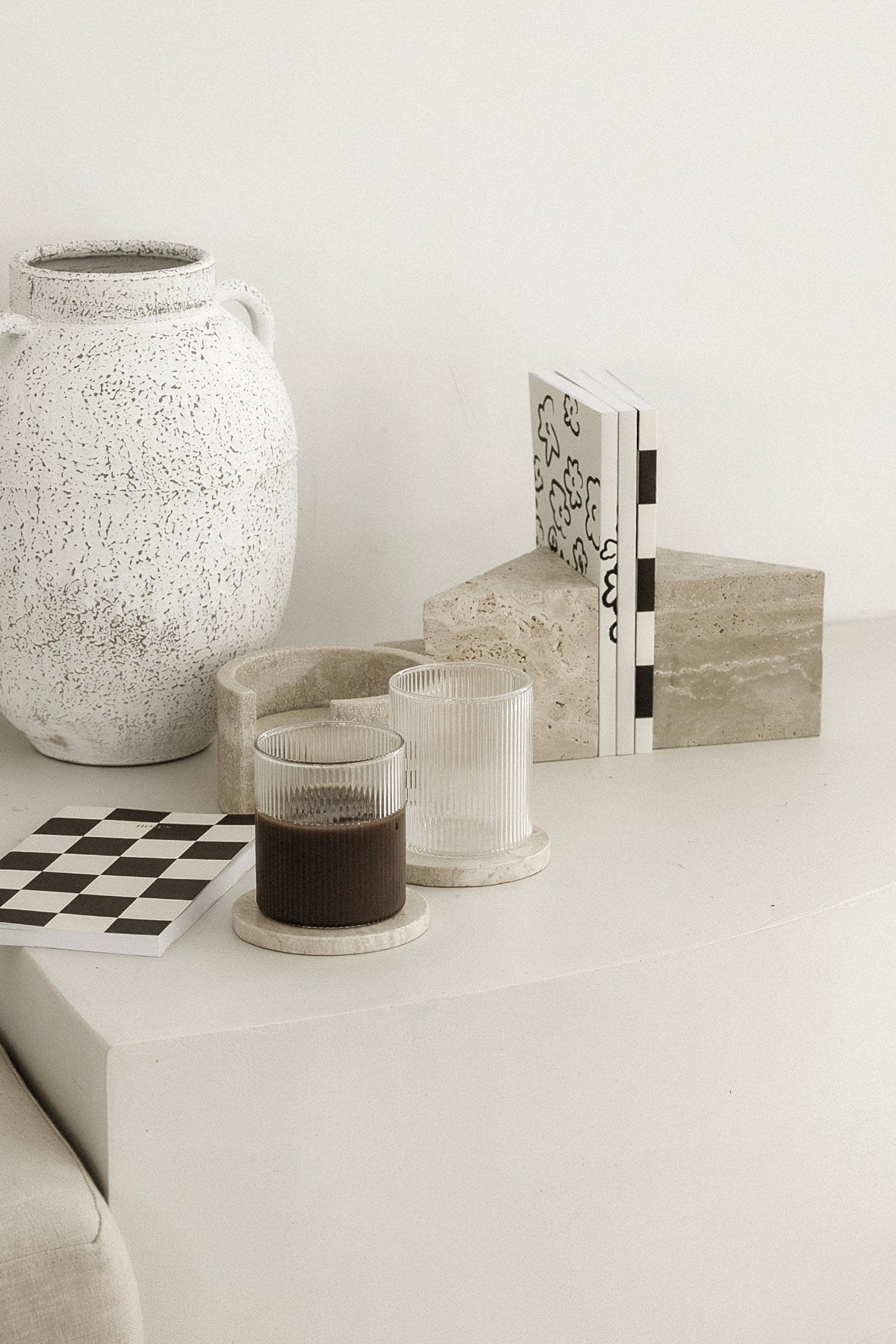 Travertine stone bookends on a side table with a stone vase and books