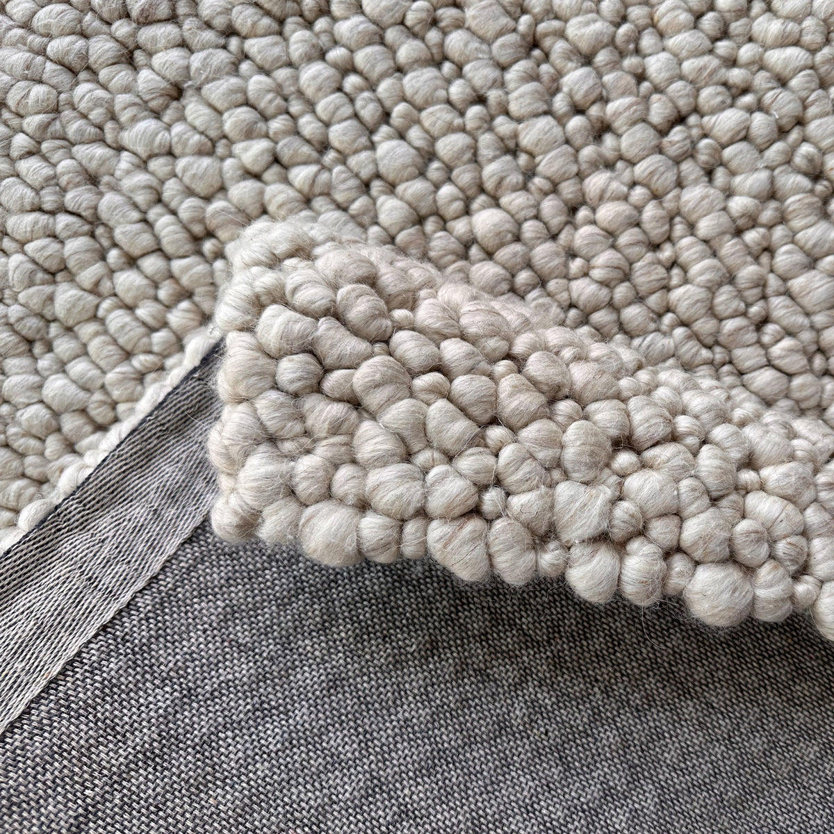Sand loop rug folded back to show the grey backing