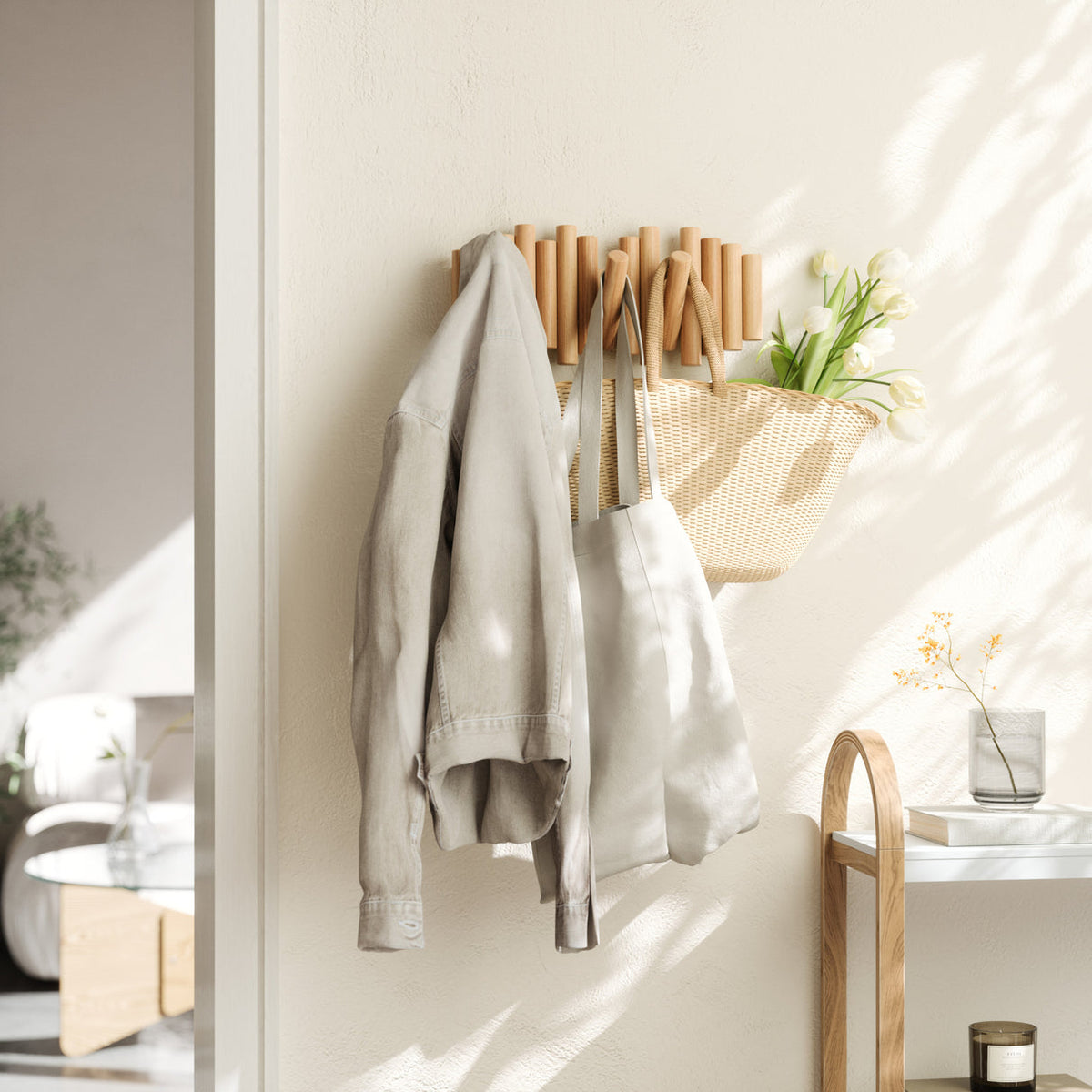 Natural pine wall hook rail with five flip hooks holding coats and a woven bag in a bright entryway.