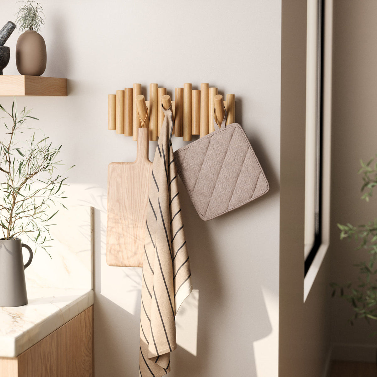 Umbra Picket rail wall hook in natural pine holding a board, tea towel and pot holder