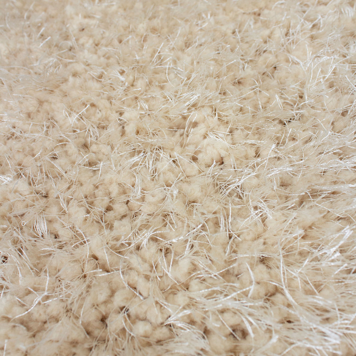 Edge of the beige shag rug folded back to show the grey backing