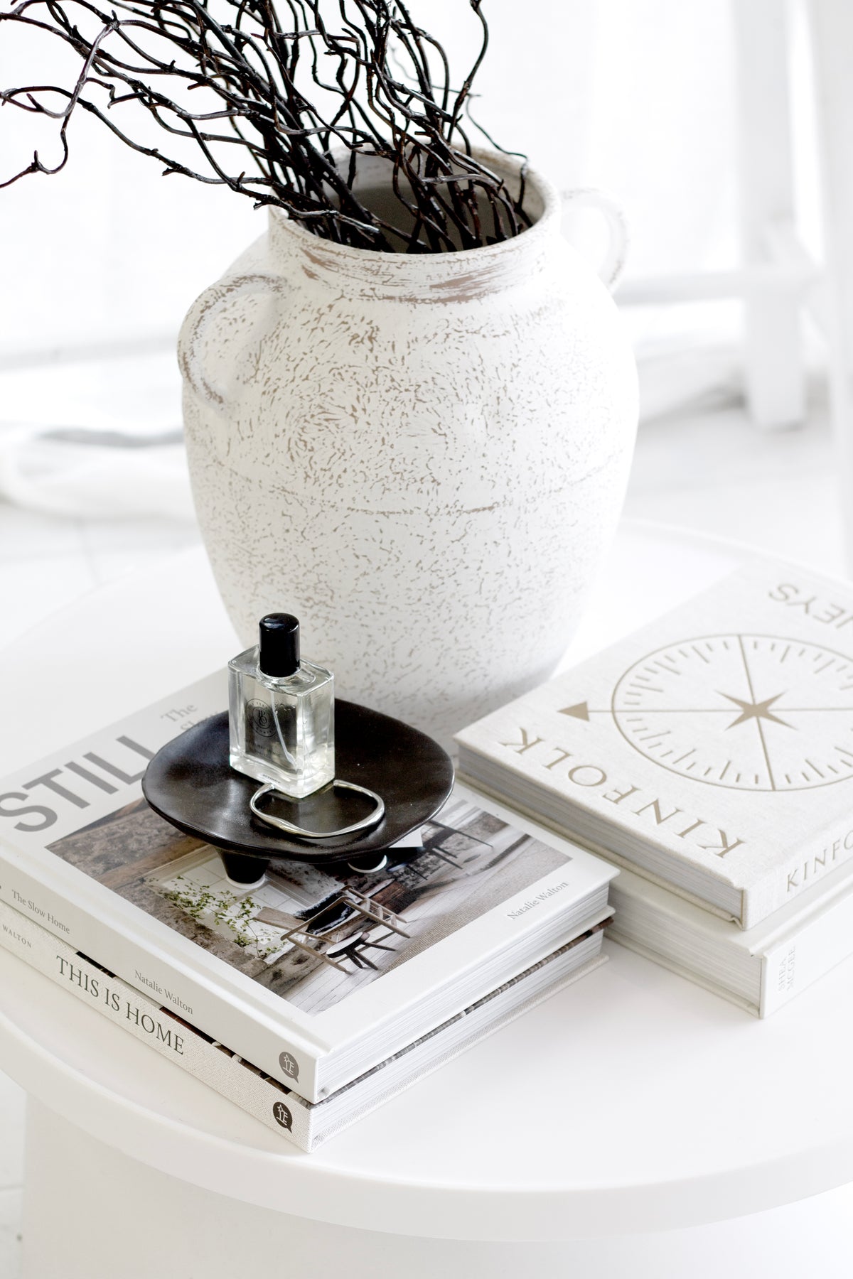 Vince ceramic vase with rustic white finish styled with dark sculptural branches beside stacked books.