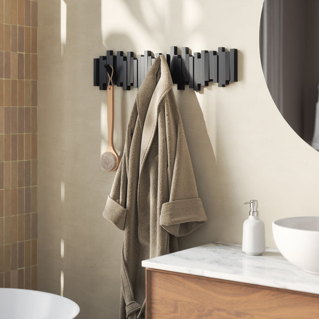 Umbra Sticks hook rack in black in a bathroom with towels and a robe hanging