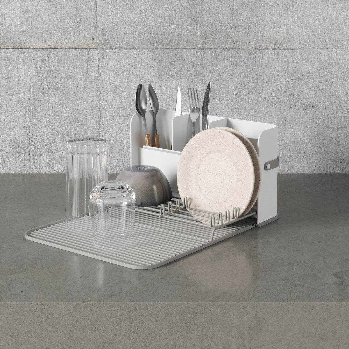 Umbra Sling dish rack and drying mat on a concrete benchtop with dishes and glasses