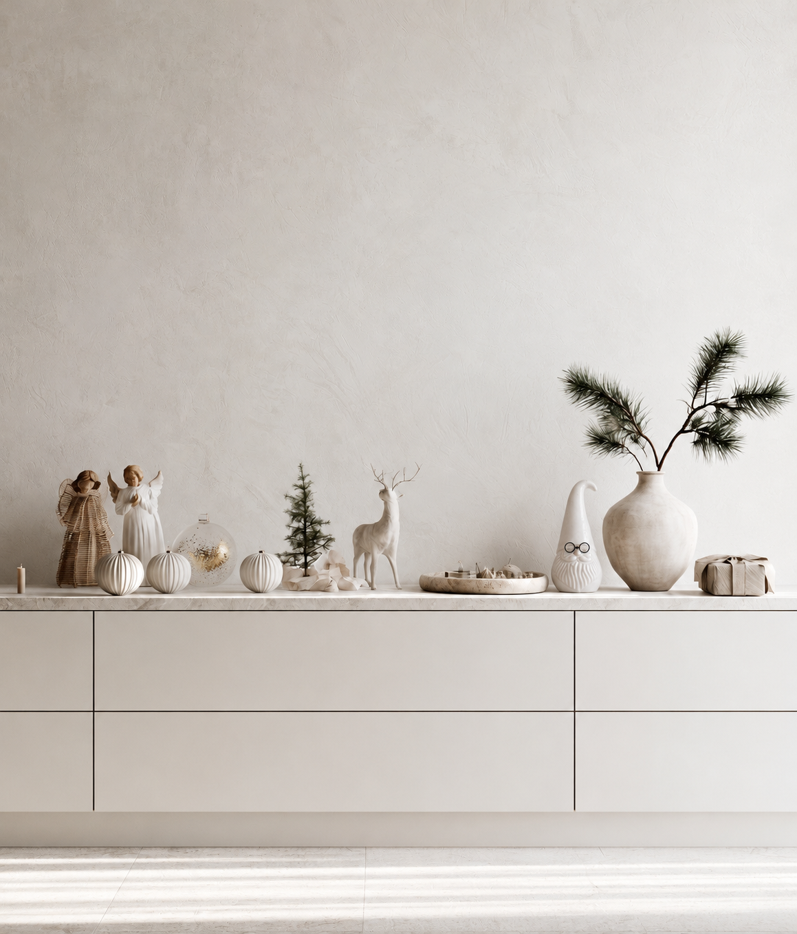 Ceramic Santa with metal glasses on a white sideboard beside a stoneware vase of pine and small Christmas figurines