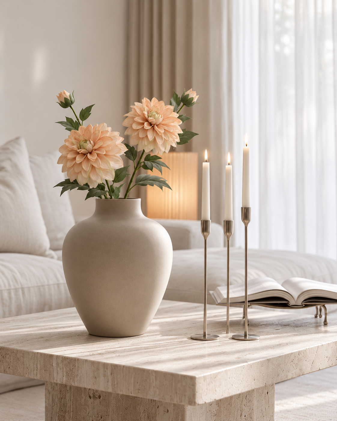 Two Heritage Dahlia stems in apricot glow in a stone vase on a travertine coffee table beside silver candlesticks