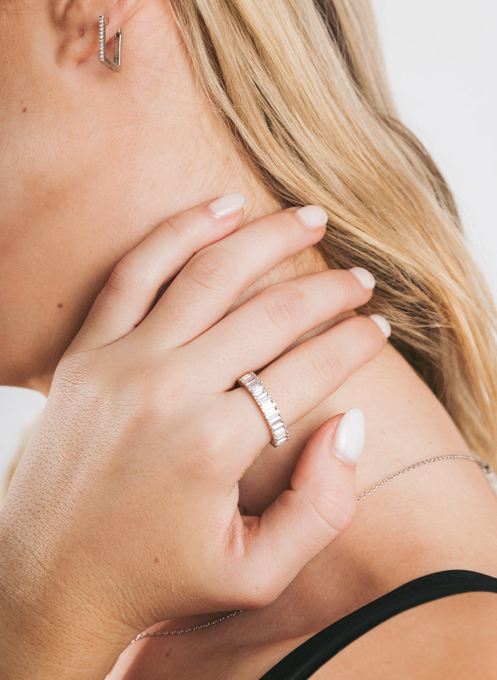 Hand on a shoulder wearing the Your Baguette Ring, silver hoop earring in view