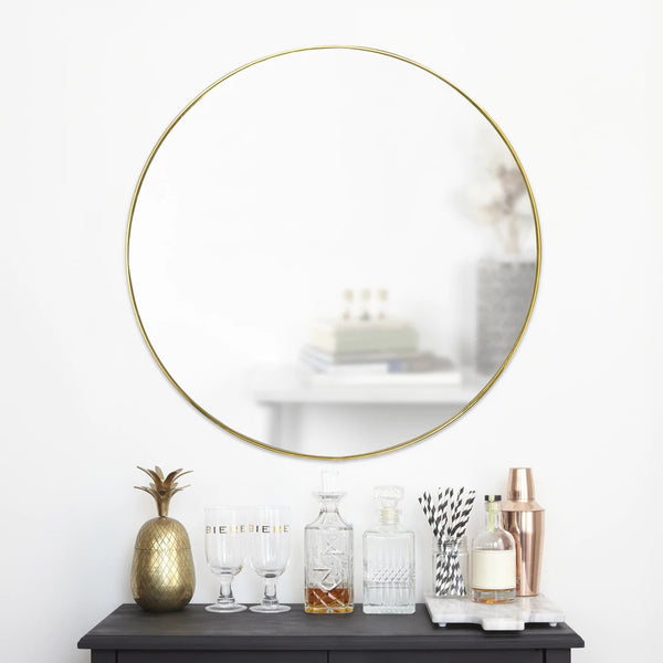 An Umbra HUBBA MIRROR 86cm BRASS with a decorative metal frame on a table, featuring a bottle of wine.