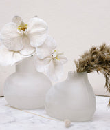 Two Zakkia Bulb Vase Orb - Frost vases, part of the handmade blown glass bulb series, with flowers in them.