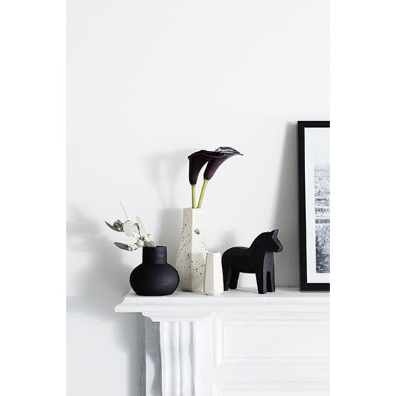 A Carved Vase Curved - Confetti mantle adorned with black Zakkia vases and a framed picture.