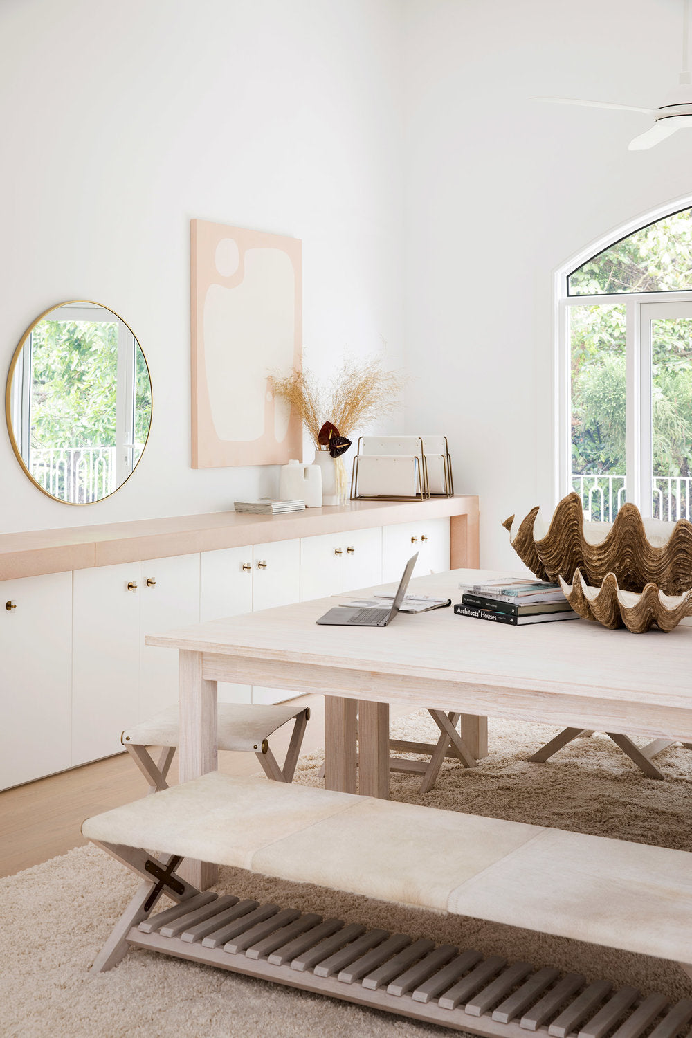 Timber dining table with a bench, round mirror and clam shell bowl