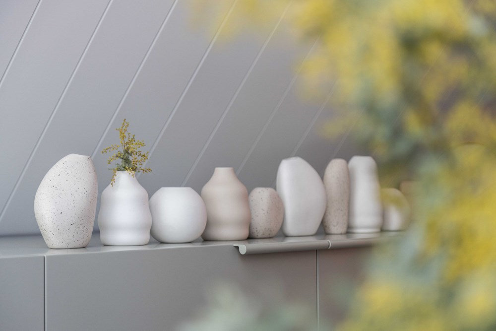 A collection of Great Harmie Vases, handcrafted by Vietnamese Artisans, are beautifully lined up on a shelf at Ned Collections.