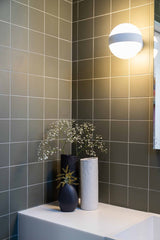 A bathroom with a Bernie Vase - Various Options sink and white tiled walls featuring a matte finish, from the Ned Collections brand.