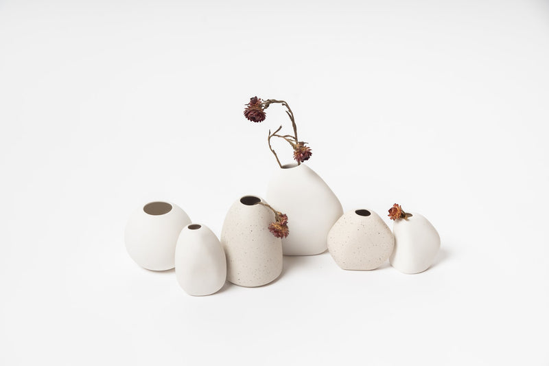 A group of Ned Collections Harmie Vases - Pod - White with organic seed-like shapes on a white surface, handcrafted by Vietnamese Artisans.