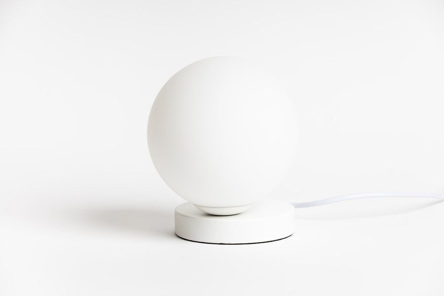 Yuri Table Lamp, a frosted glass globe on a round white steel base