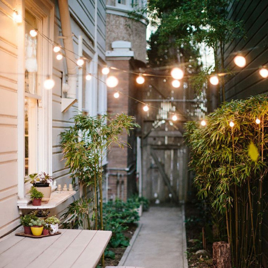 Festoon lights hung across a garden patio for outdoor entertaining