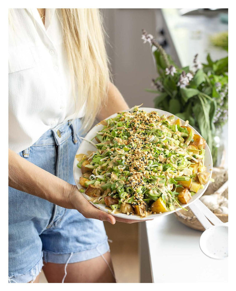 A woman is holding a plate of Raw & Free plant-based salad by Books.