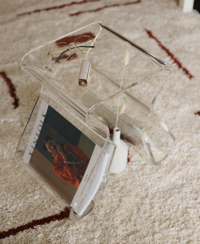 Magino stool on a patterned rug with a magazine in the rack and sunglasses on top