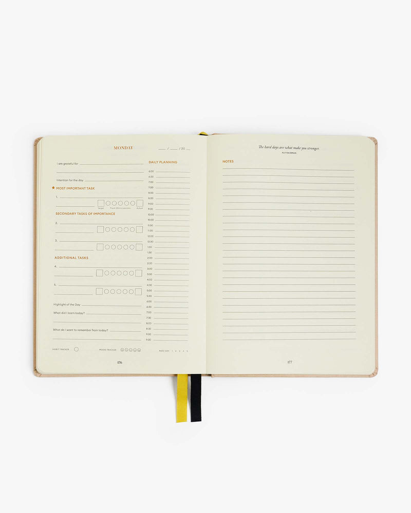 An Intelligent Change Productivity Planner with a black cover and an Intelligent Change yellow pen.
