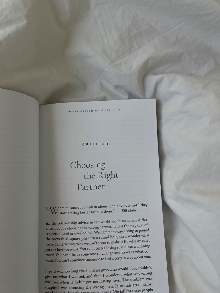 Book open to a chapter page on white bedding