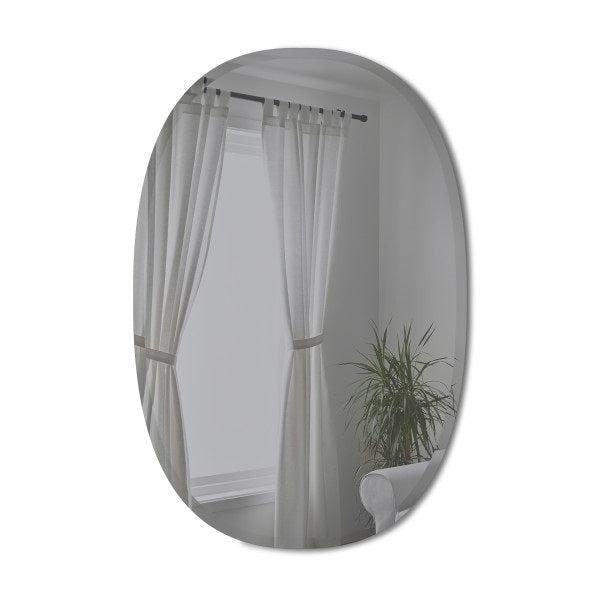 Umbra Bevy oval mirror in smoke glass on a wall beside curtains and a plant