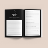 A black and white Visions & Actions Journal by Collective Hub with the words 'monthly review' for keeping track of goals and documenting reflections.