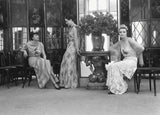 Three fashion couturiers in Little Book of Chanel dresses sitting in front of a vase.