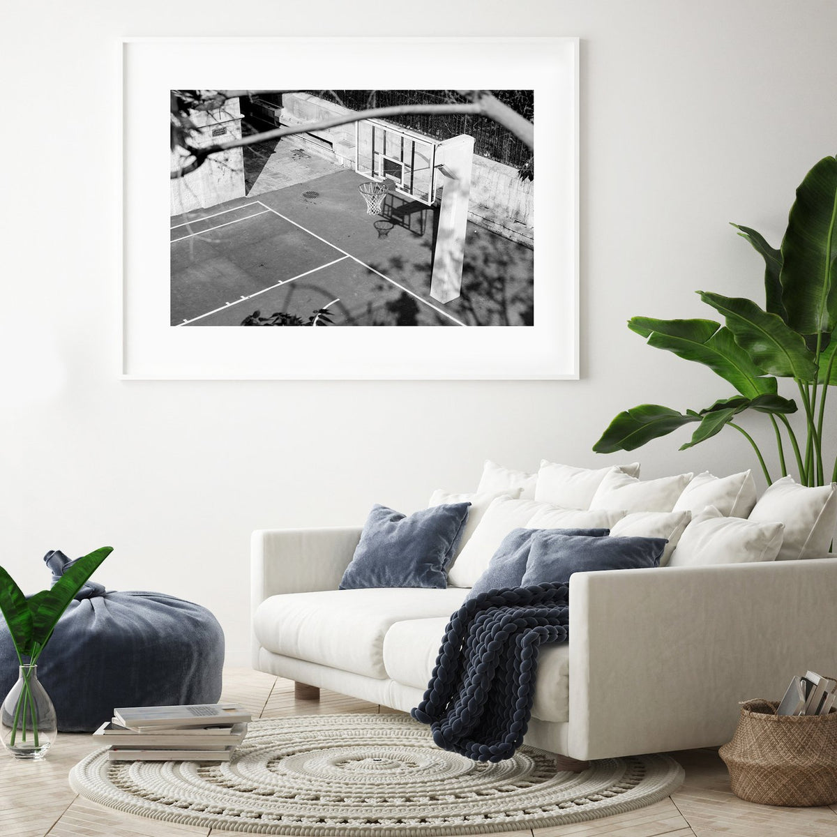 Basketball hoop print in a white frame above a cream sofa with navy cushions