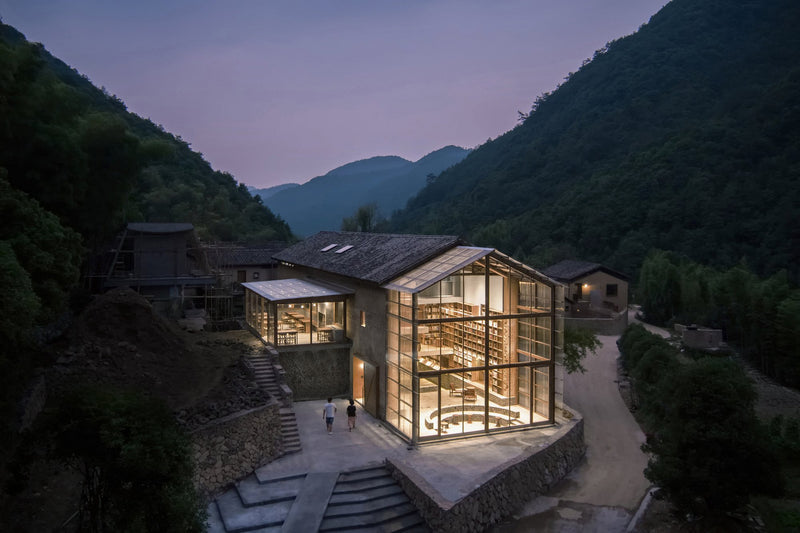 A glass house in the mountains at dusk, featuring Chinese architecture and designed by architects skilled in the art of integrating nature and modernity, like BEAUTY AND THE EAST books.