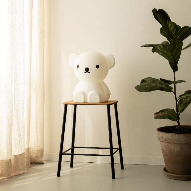 Boris lamp on a black stool beside a fig tree in a bright room
