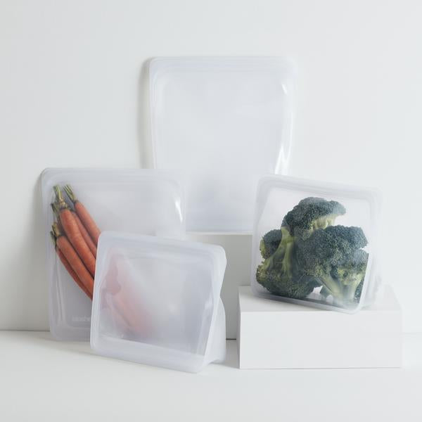 Four clear Stasher bags in different sizes holding carrots, broccoli and other vegetables