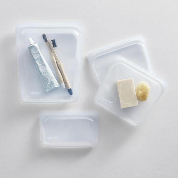Clear Stasher bags in several sizes holding toothbrushes, toothpaste and a bar of soap