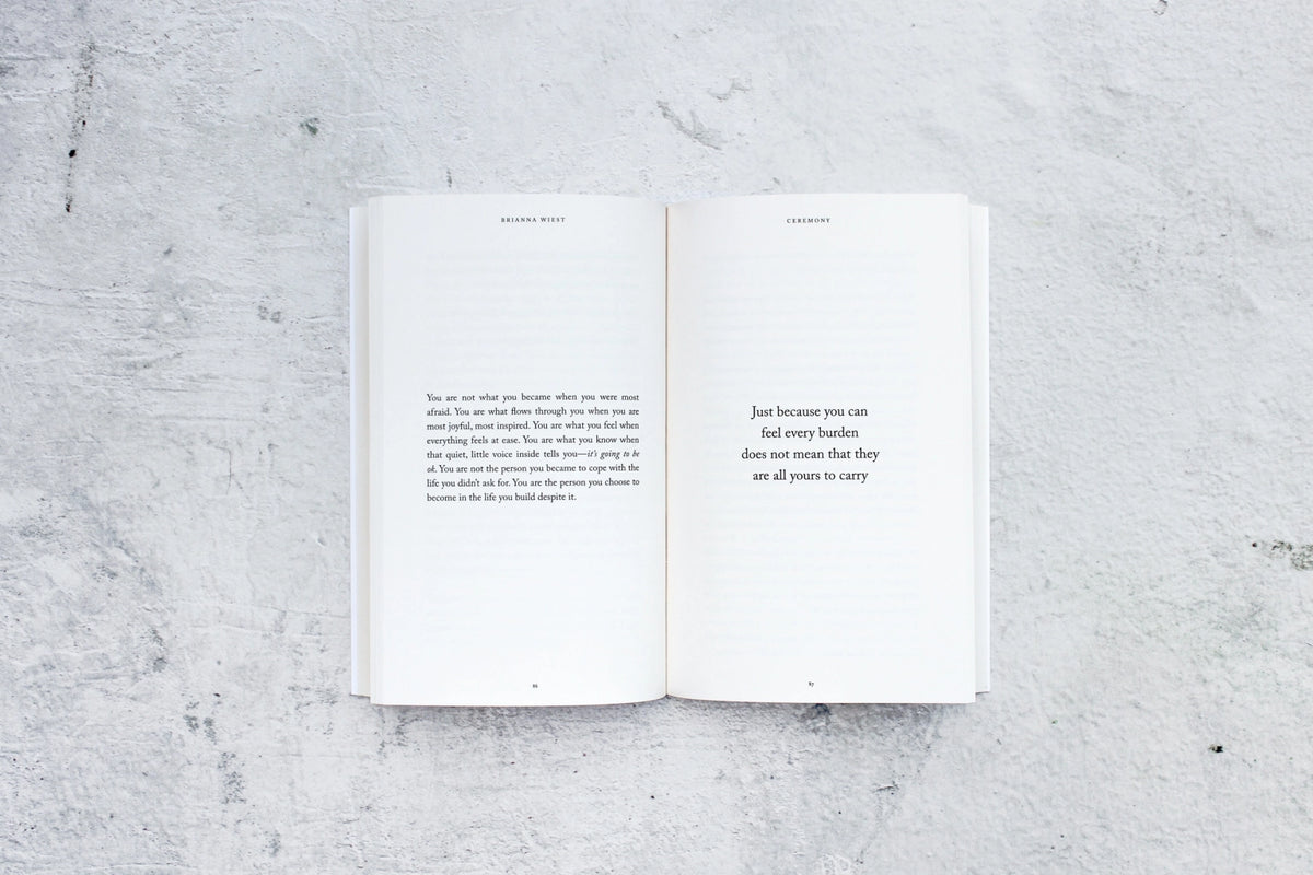 An open book on a concrete surface with Ceremony | Brianna Wiest design books by Thought Catalog.
