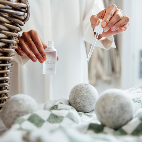 A woman from Scandinavia displays a basket of Ecoya Dryer Ball Fragrance Droppers alongside her bottle of Ecoya laundry soap.