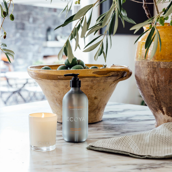 An Ecoya Kitchen | Fragranced Hand Wash 450ml sits on a table next to a bowl of olives.