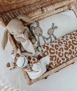 A wicker basket with a GIRAFFE SNUGGLY comforter and a teddy bear made of Oeko-tex® Certified Cotton from Bengali Collections.