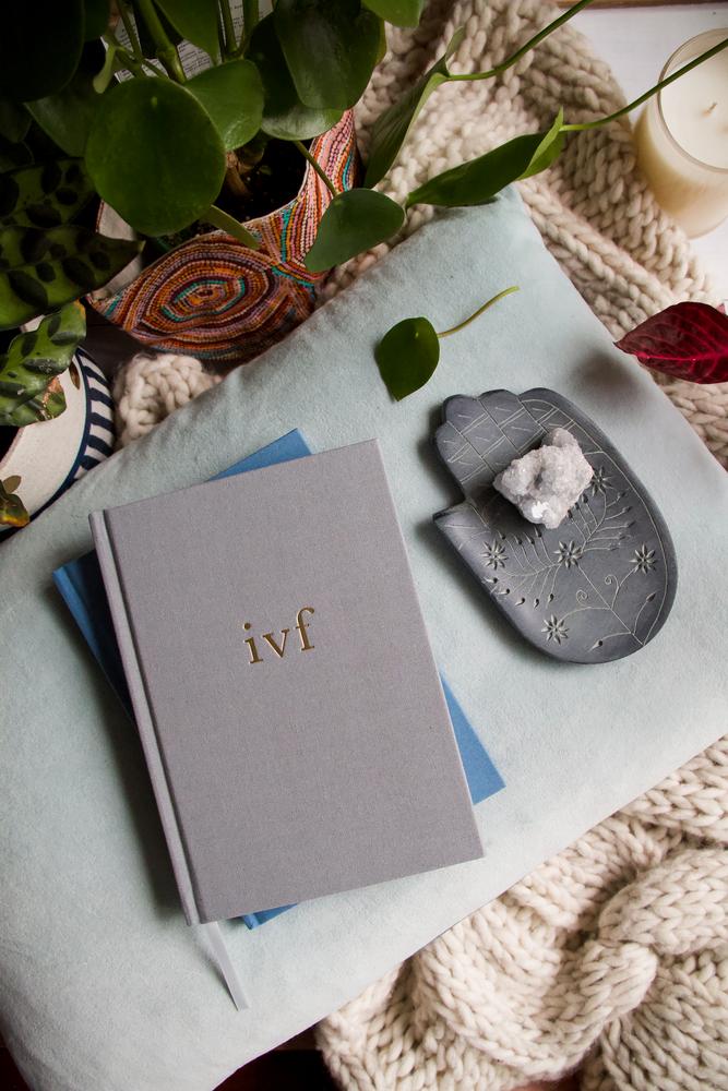 Grey IVF Journey Journal on a knitted throw with a small dish, roses and greenery