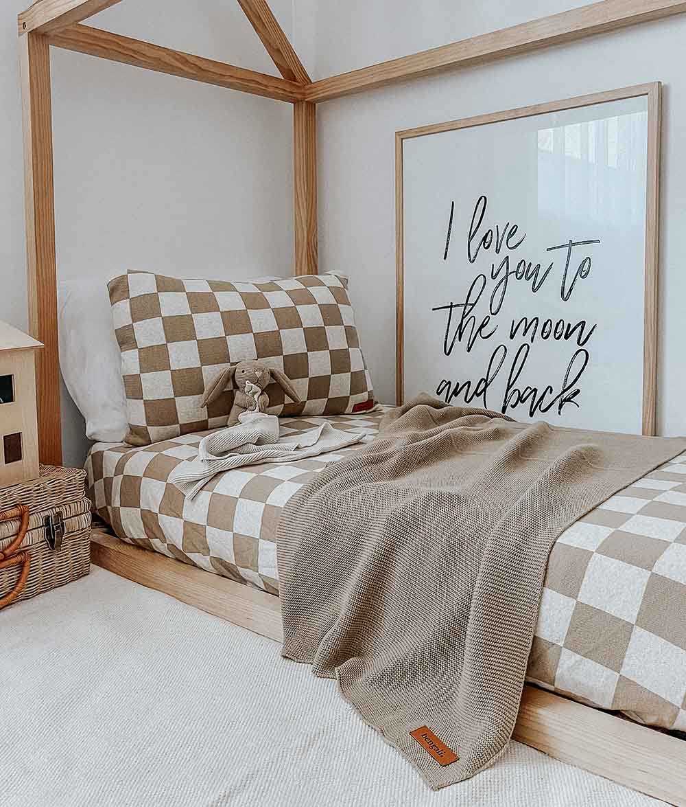 House frame bed made up with khaki gingham check bedding and a knitted throw