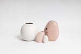 Three pink and white Ned Collections Harmie vases with organic seed-like shapes on a white surface.