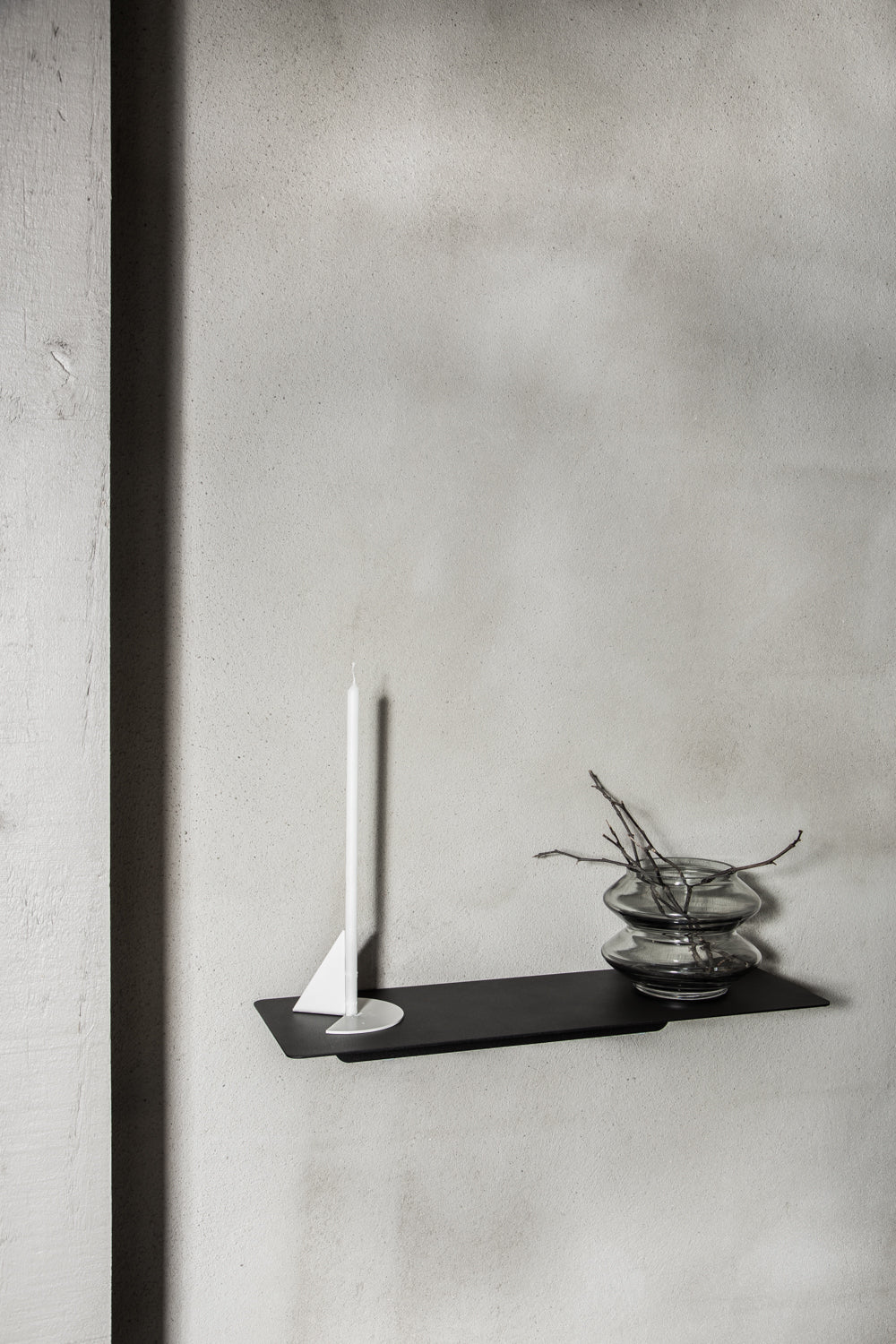 FOLD Ledge in black on a concrete wall with a candle and a small plant
