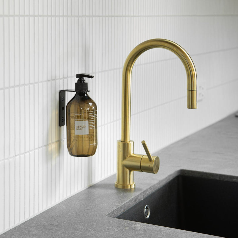A kitchen sink with a brass faucet and soap dispenser, featuring the FOLD Bottle Holder ∙ Black by Made of Tomorrow.