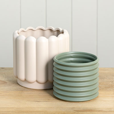 A pair of green and pink Berlin Self Watering Planters - Eucalypt by Potted on a wooden table with internal drainage saucer.