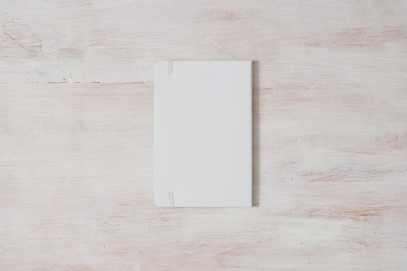 A white Morning Pages — Journal sitting on top of a wooden surface.