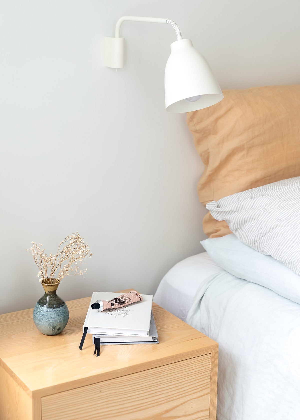 A bedside table with the Our Spaces - Contemporary New Zealand Interiors lamp next to it.