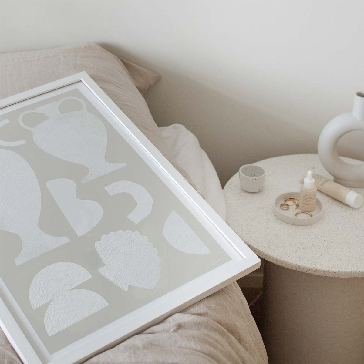 Painted Objects print in a white frame leaning on a sofa by a side table