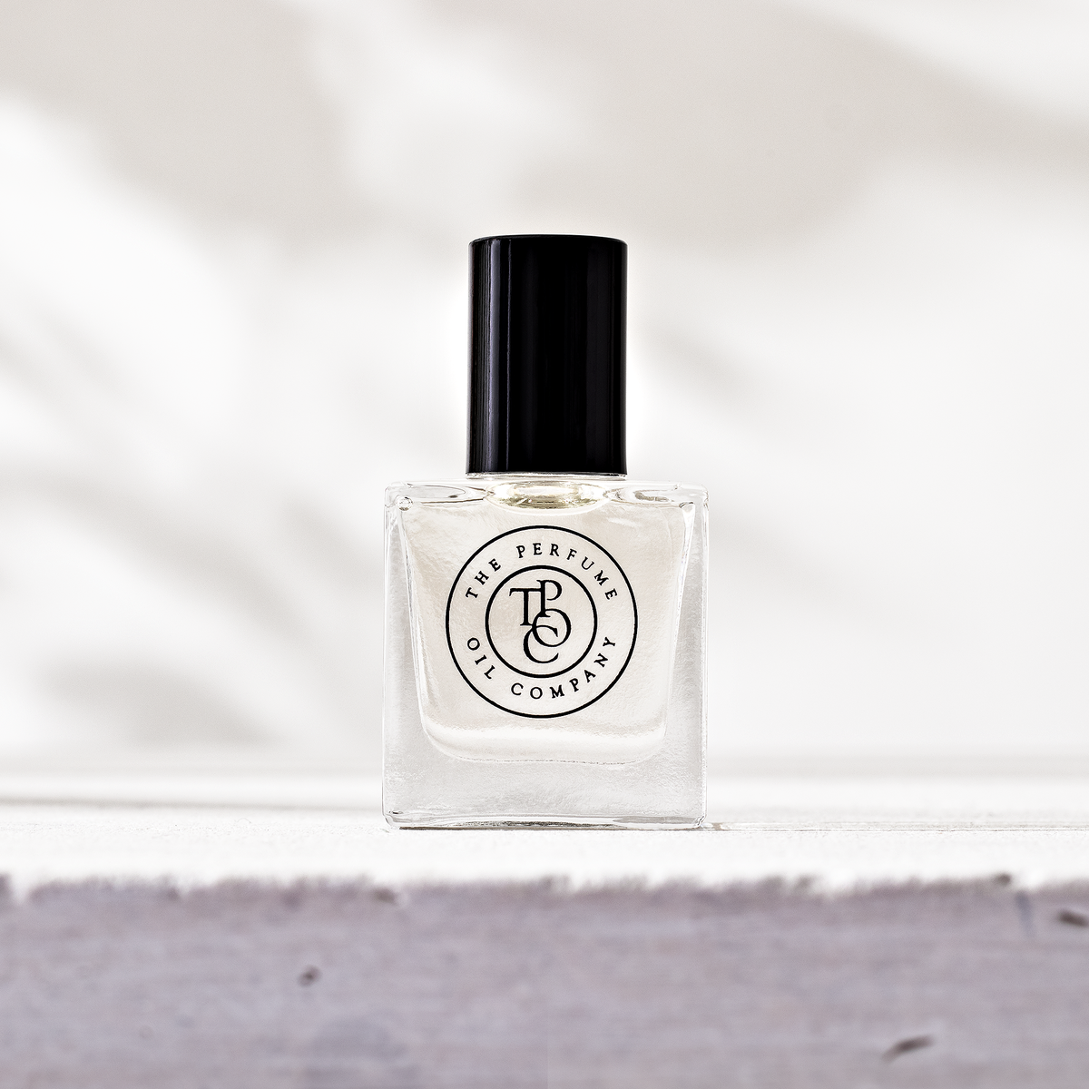 Perfume oil bottle on a grey stone ledge against a white backdrop