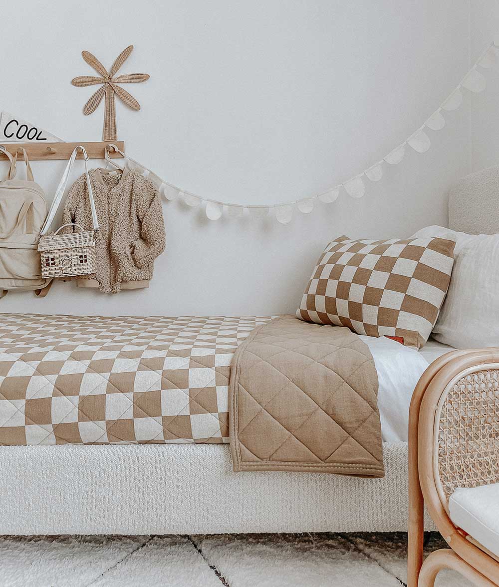 Kids bed with the khaki gingham check pillowcase, a quilted khaki throw and a rattan chair