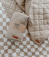 A REVERSIBLE QUILT - KHAKI GINGHAM on a bed with a checkered pattern by Bengali Collections.